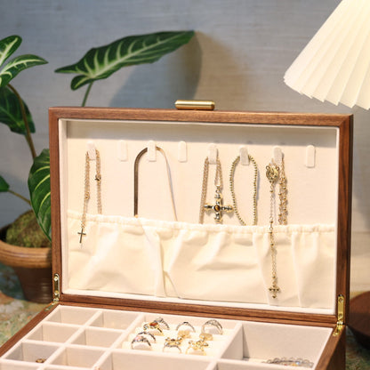 Jewelry box with necklaces and earrings on a table with a lamp and plant in the background