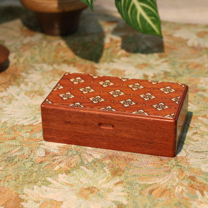 Wooden jewelry box with decorative patterns on a floral-patterned surface
