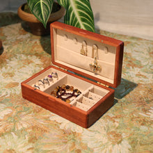 Wooden jewelry box with jewelry on a floral-patterned surface