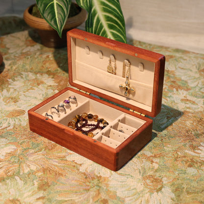 Wooden jewelry box with jewelry on a floral-patterned surface