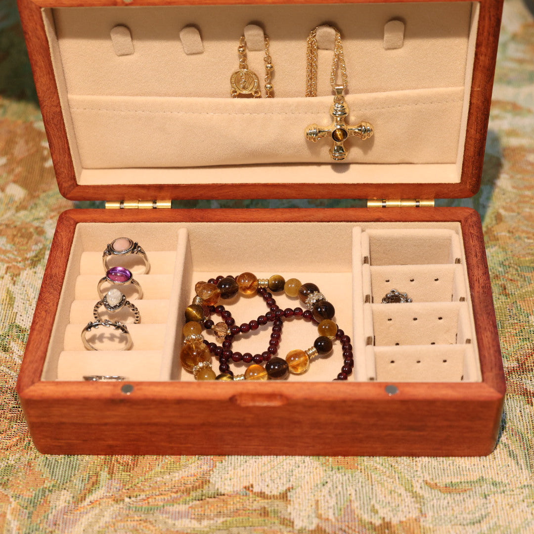 Open jewelry box with necklaces and earrings on a patterned surface