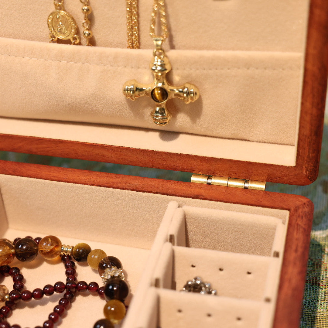 Open jewelry box with necklaces and a ring on a patterned surface