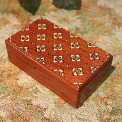 Wooden jewelry box with intricate patterns on a floral tablecloth
