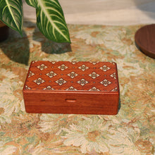 Wooden jewelry box with intricate patterns on a floral-patterned surface