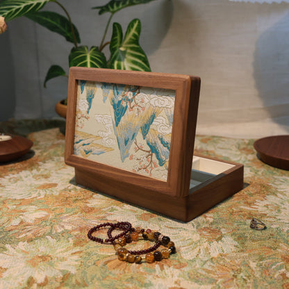 Wooden jewelry box with decorative items on a floral-patterned surface