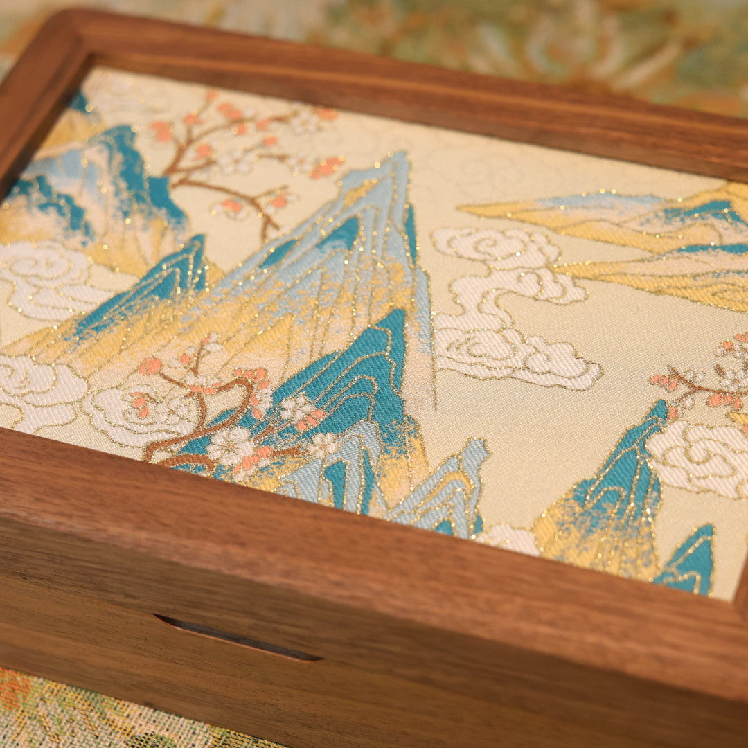 Wooden box with a decorative lid featuring mountain and cloud design.