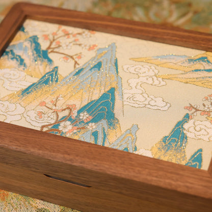 Wooden box with a decorative lid featuring mountain and cloud design.