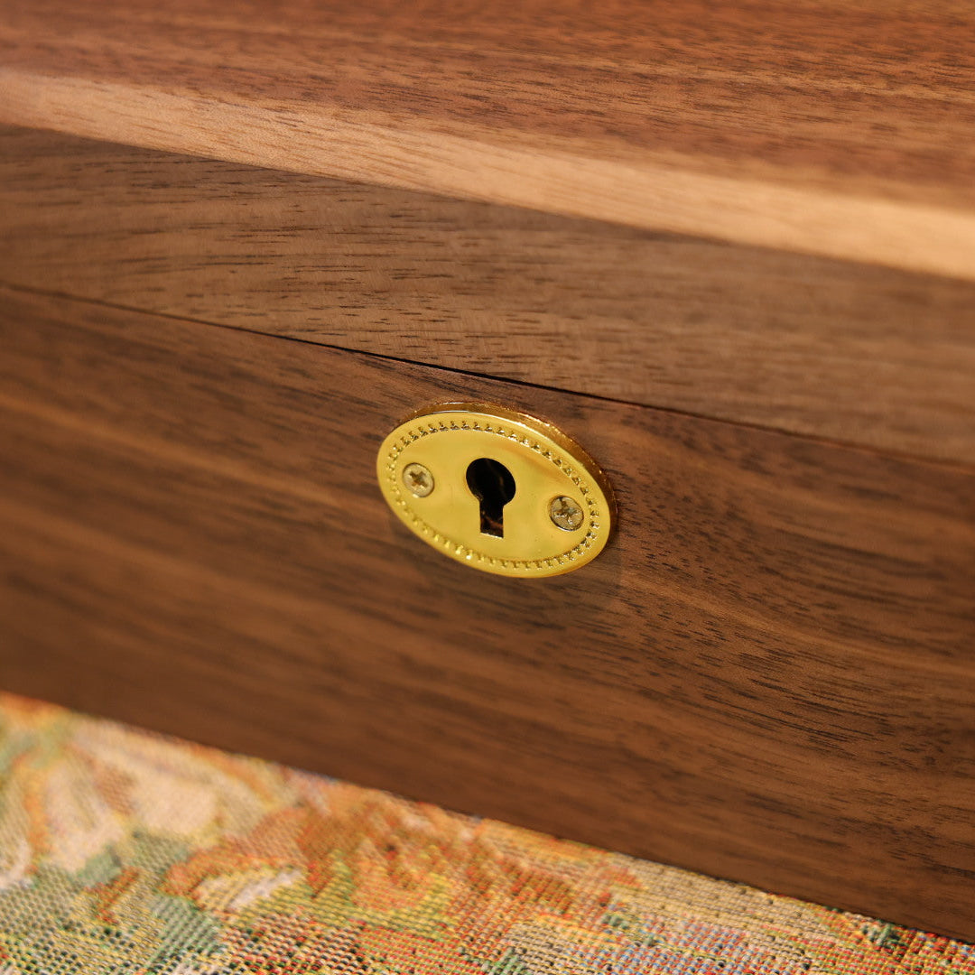 Close-up of a wooden drawer with a brass lock on a patterned fabric background