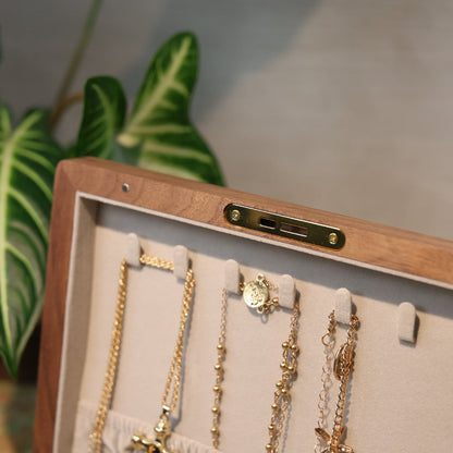 Wooden jewelry box with gold necklaces on a neutral background