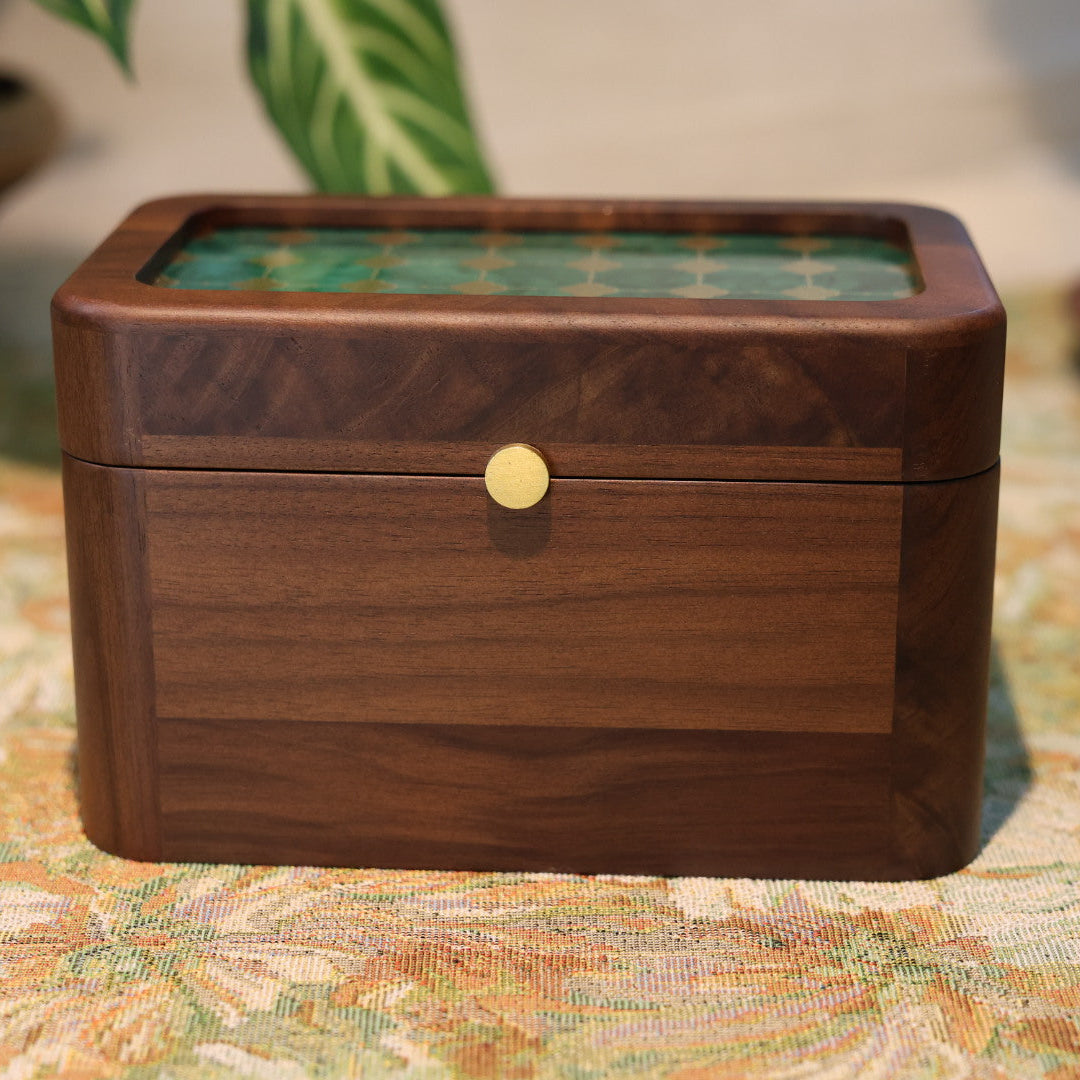 Wooden jewelry box with glass lid on a floral tablecloth