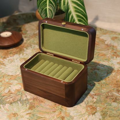 Wooden jewelry box with green interior on a patterned surface