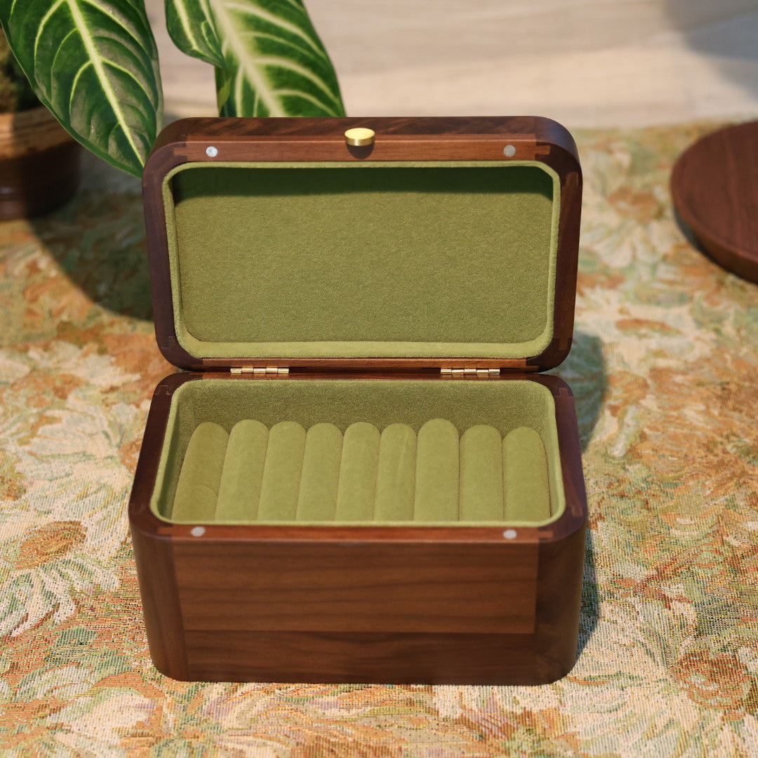 Wooden jewelry box with green interior on a patterned surface