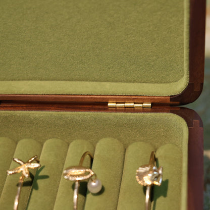 Gold earrings in a green jewelry box on a textured surface