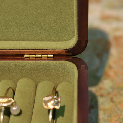 Gold earrings in a green jewelry box with a blurred background