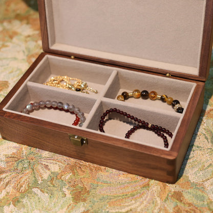 Wooden jewelry box with compartments containing bracelets on a floral-patterned surface