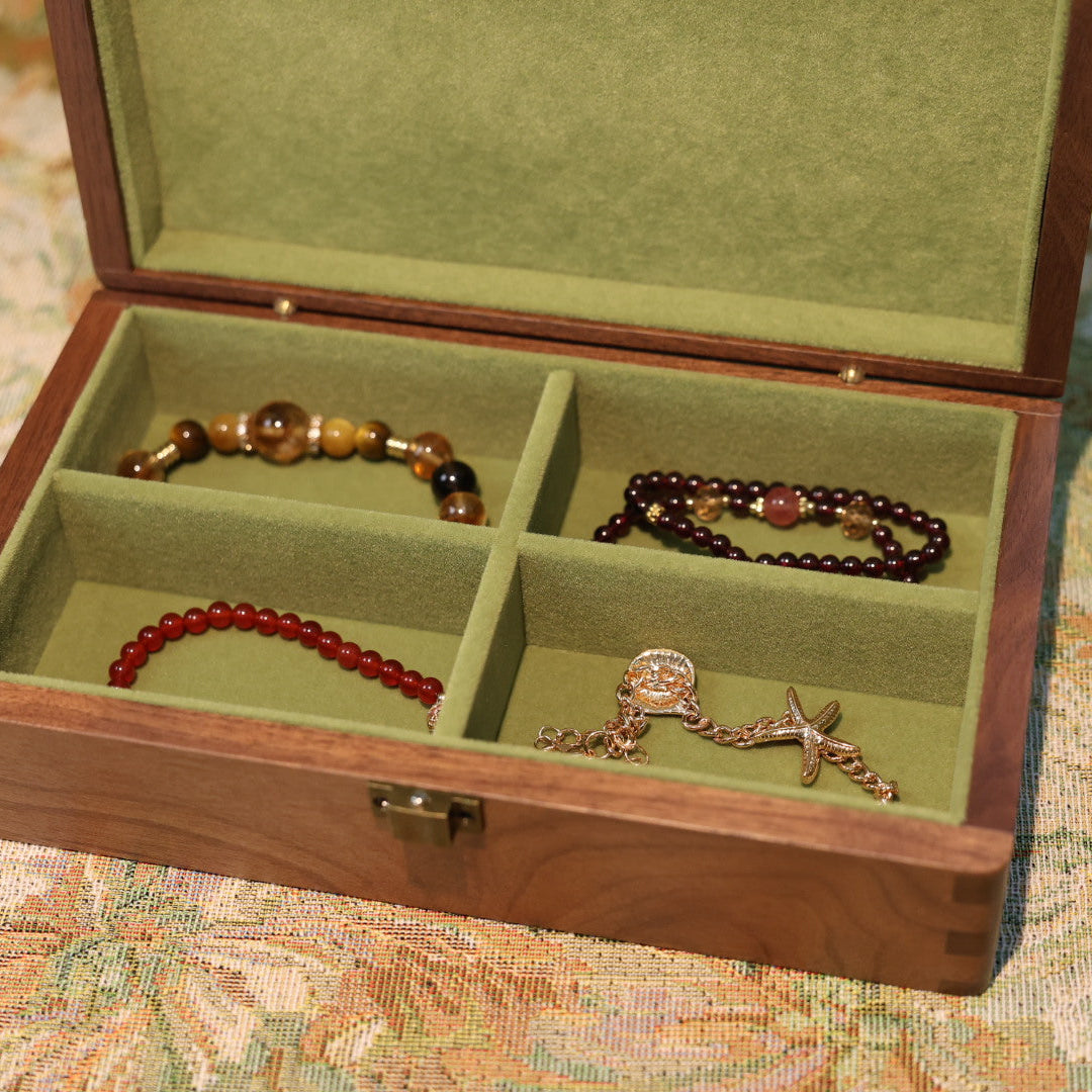 Jewelry box with compartments containing various pieces of jewelry on a patterned surface.