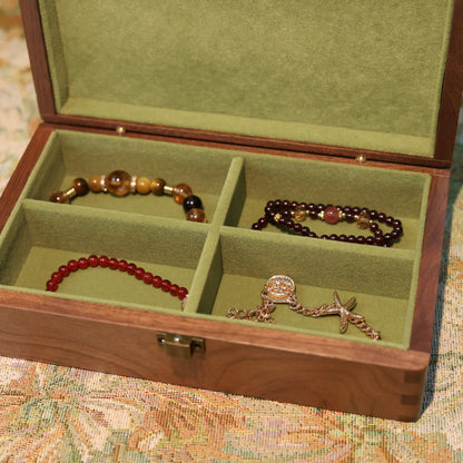 Jewelry box with compartments containing various pieces of jewelry on a patterned surface.
