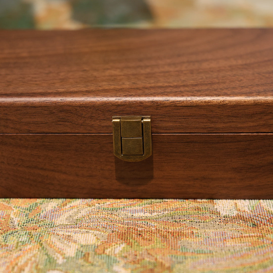 Wooden jewelry box with a gold clasp on a patterned surface