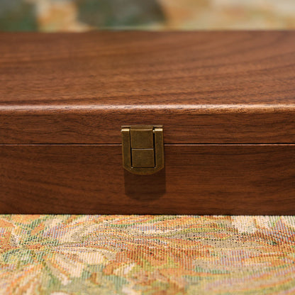 Wooden jewelry box with a gold clasp on a patterned surface