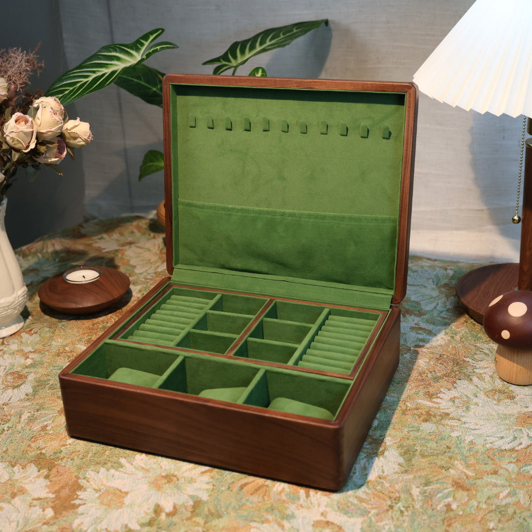 Open jewelry box with green interior on a patterned tablecloth.