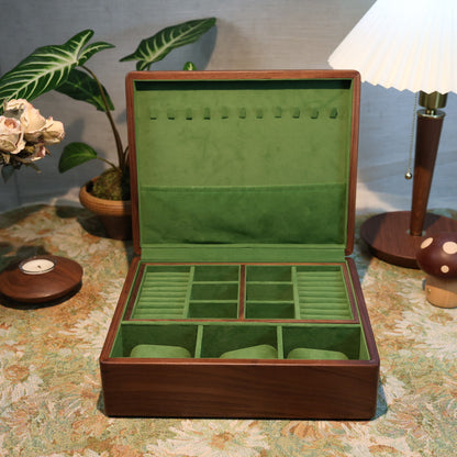 Wooden jewelry box with green interior on a patterned tablecloth.