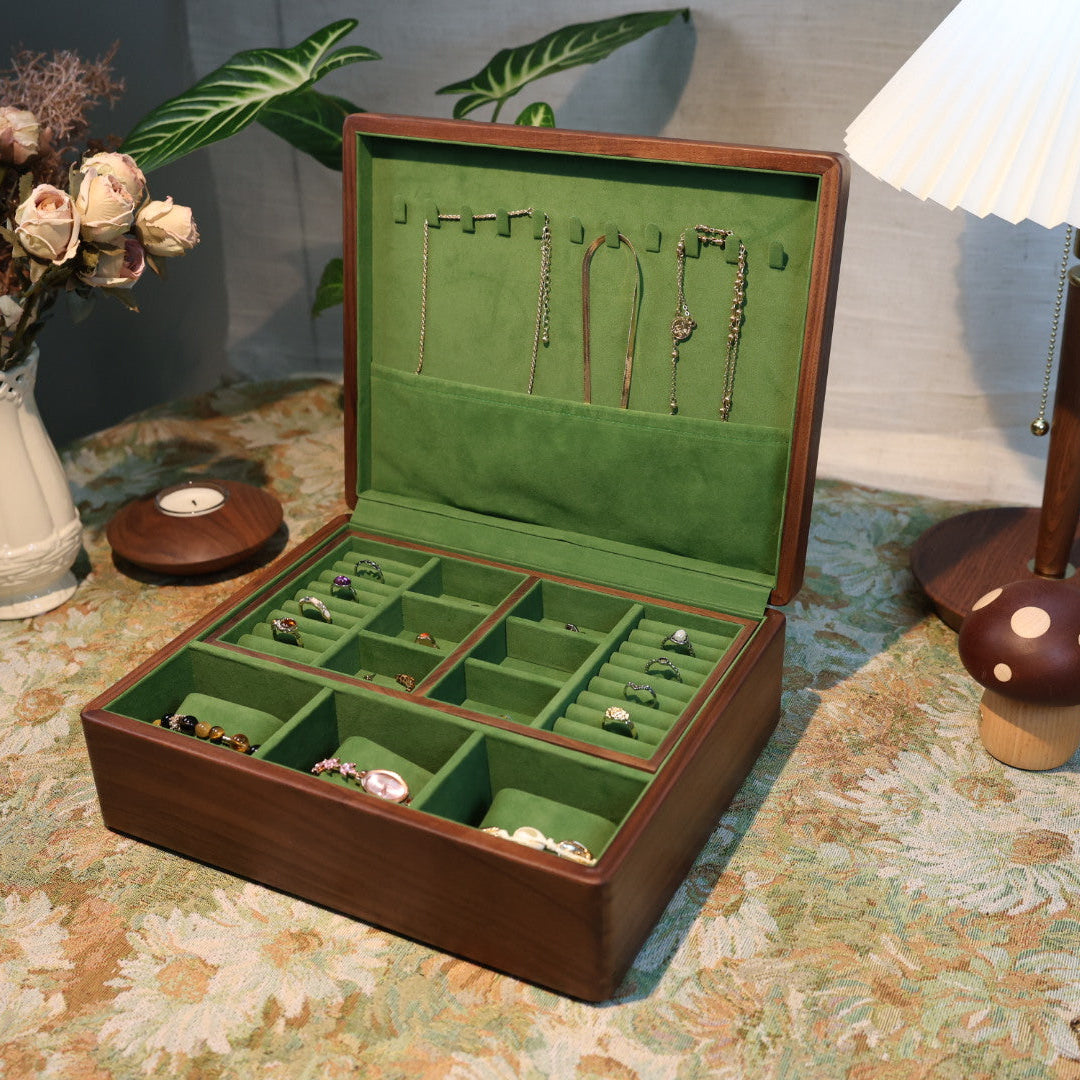 Open jewelry box with green interior on a floral-patterned tablecloth.