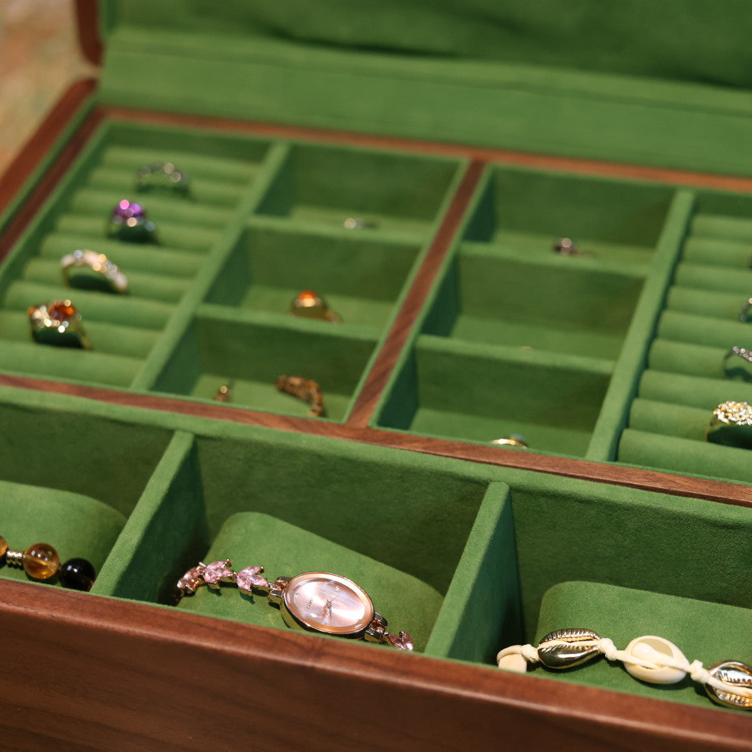 Jewelry box with green interior holding various jewelry items.