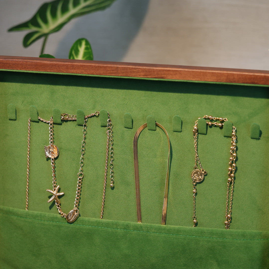 Green jewelry display with necklaces on a wooden frame