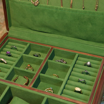 Green jewelry box with rings and necklaces on a patterned surface