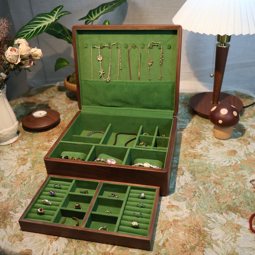 Open jewelry box with green interior on a patterned tablecloth.