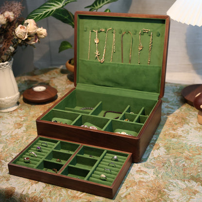Open jewelry box with green interior on a patterned tablecloth.