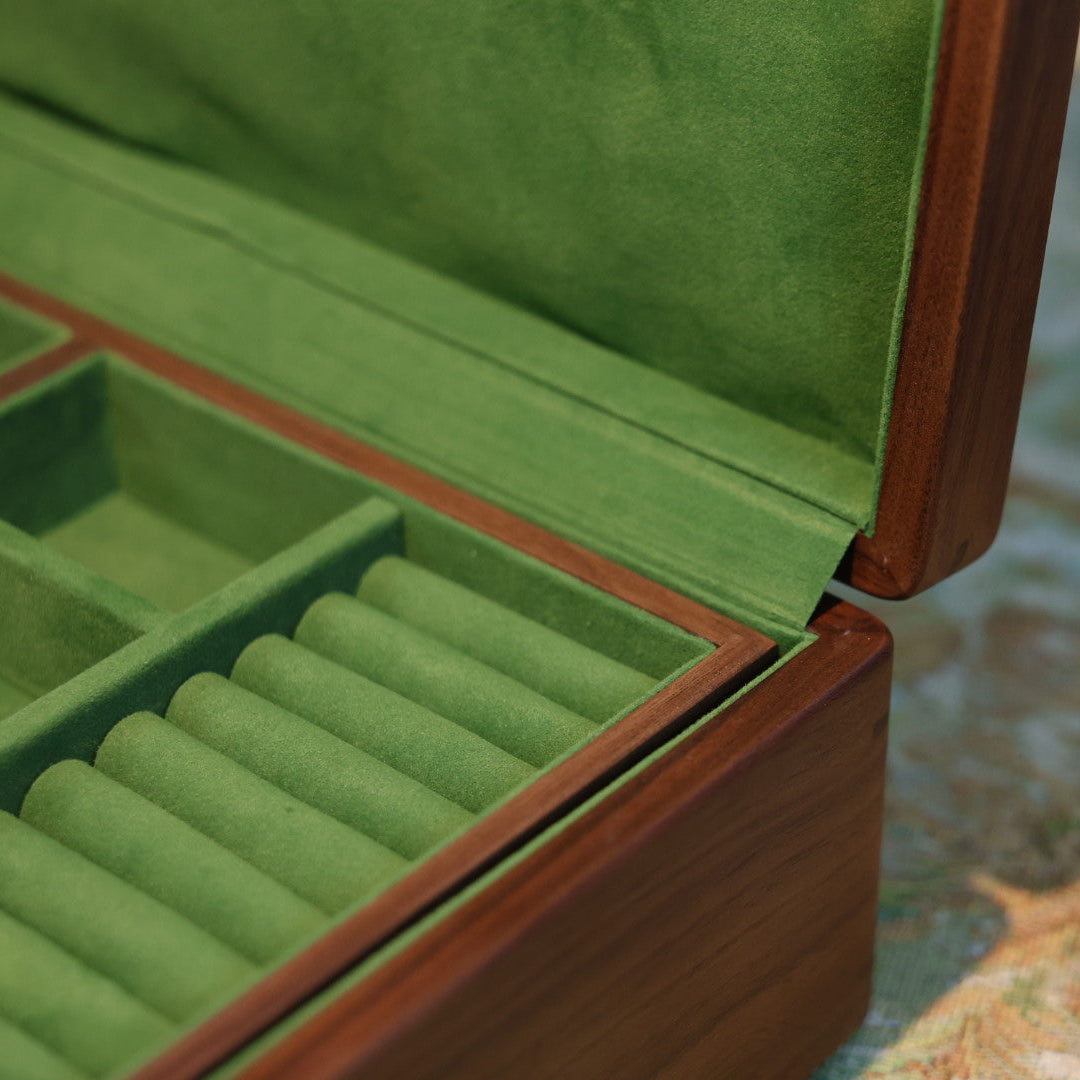 Green jewelry box with compartments on a patterned surface