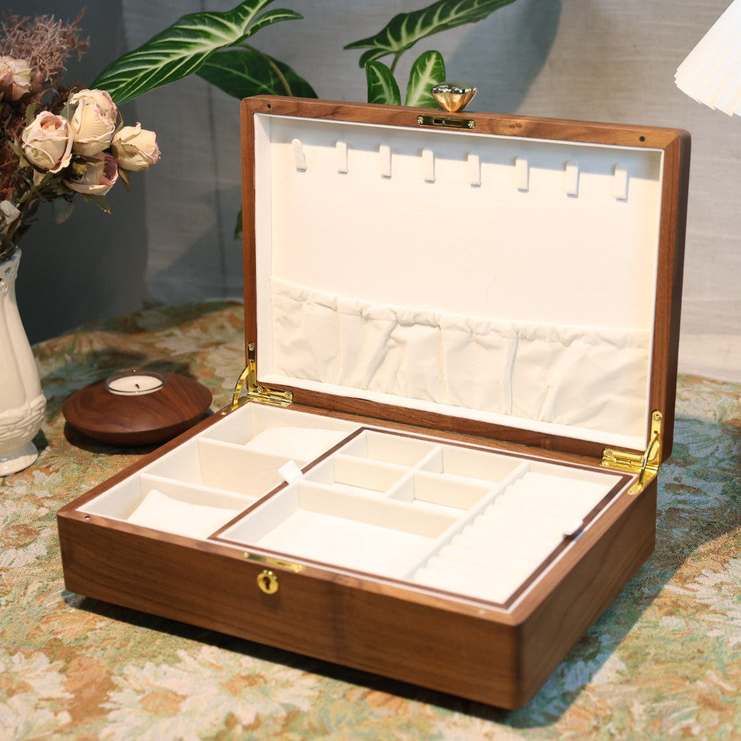 Wooden jewelry box on a decorative table with a vase and lamp in the background