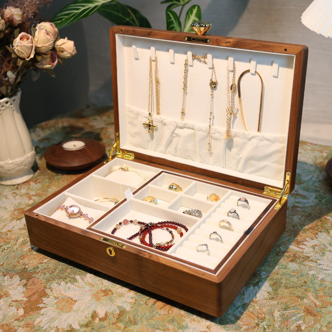 Open jewelry box with various necklaces on a patterned tablecloth.