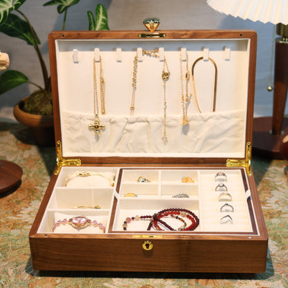 Open jewelry box with various necklaces and accessories on a patterned surface.
