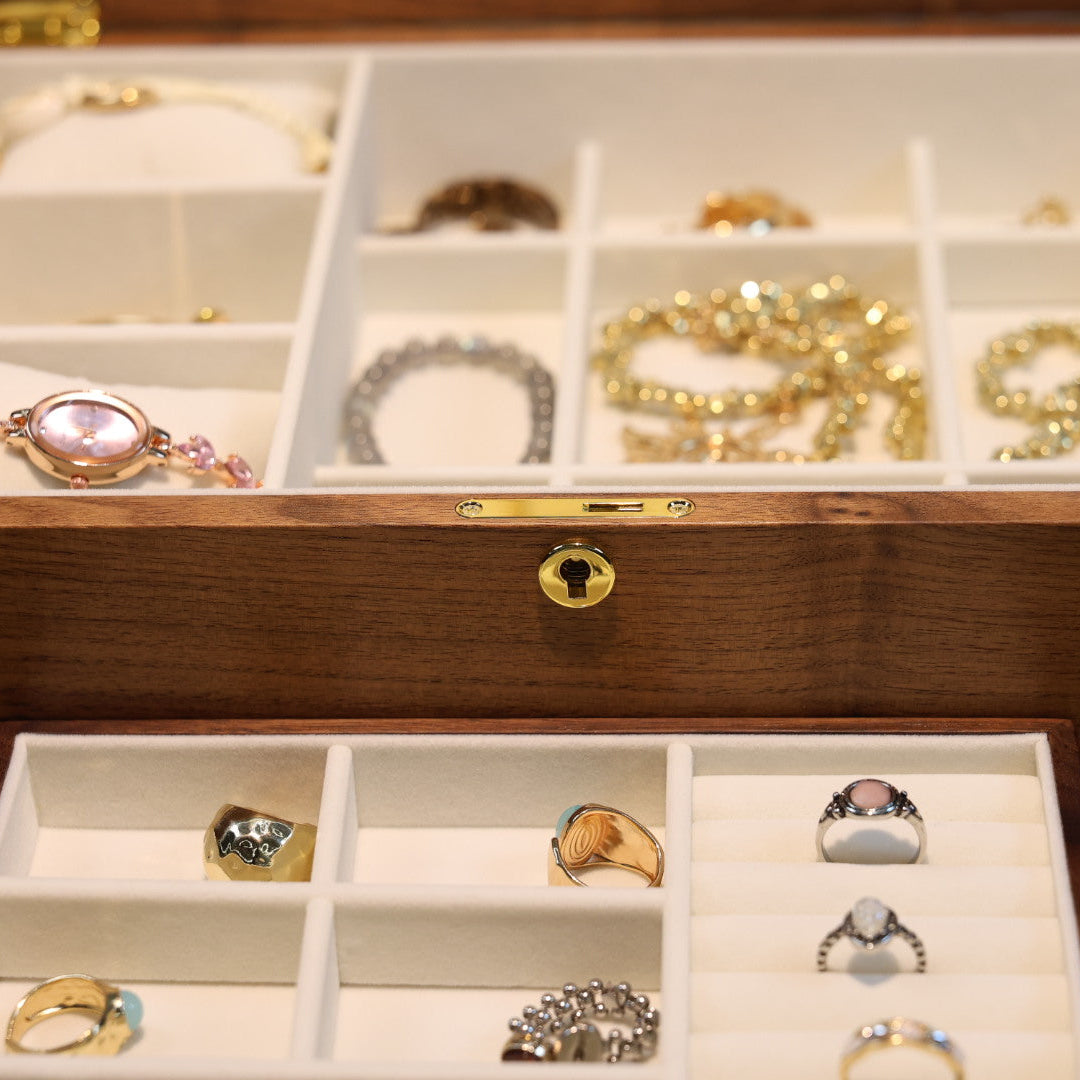 Wooden jewelry box with compartments containing various pieces of jewelry.