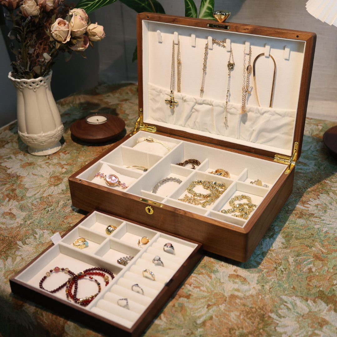 Open jewelry box with various jewelry items on a patterned tablecloth.