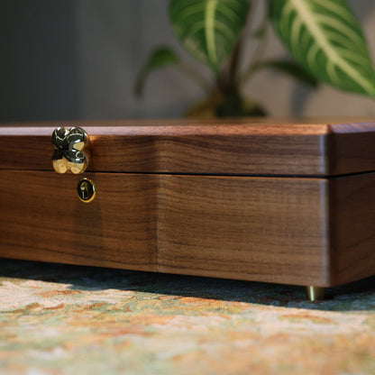 Wooden jewelry box with a gold clasp on a patterned surface