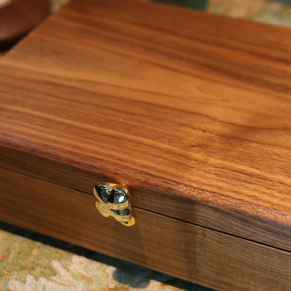 Wooden jewelry box with a gold clasp on a patterned surface