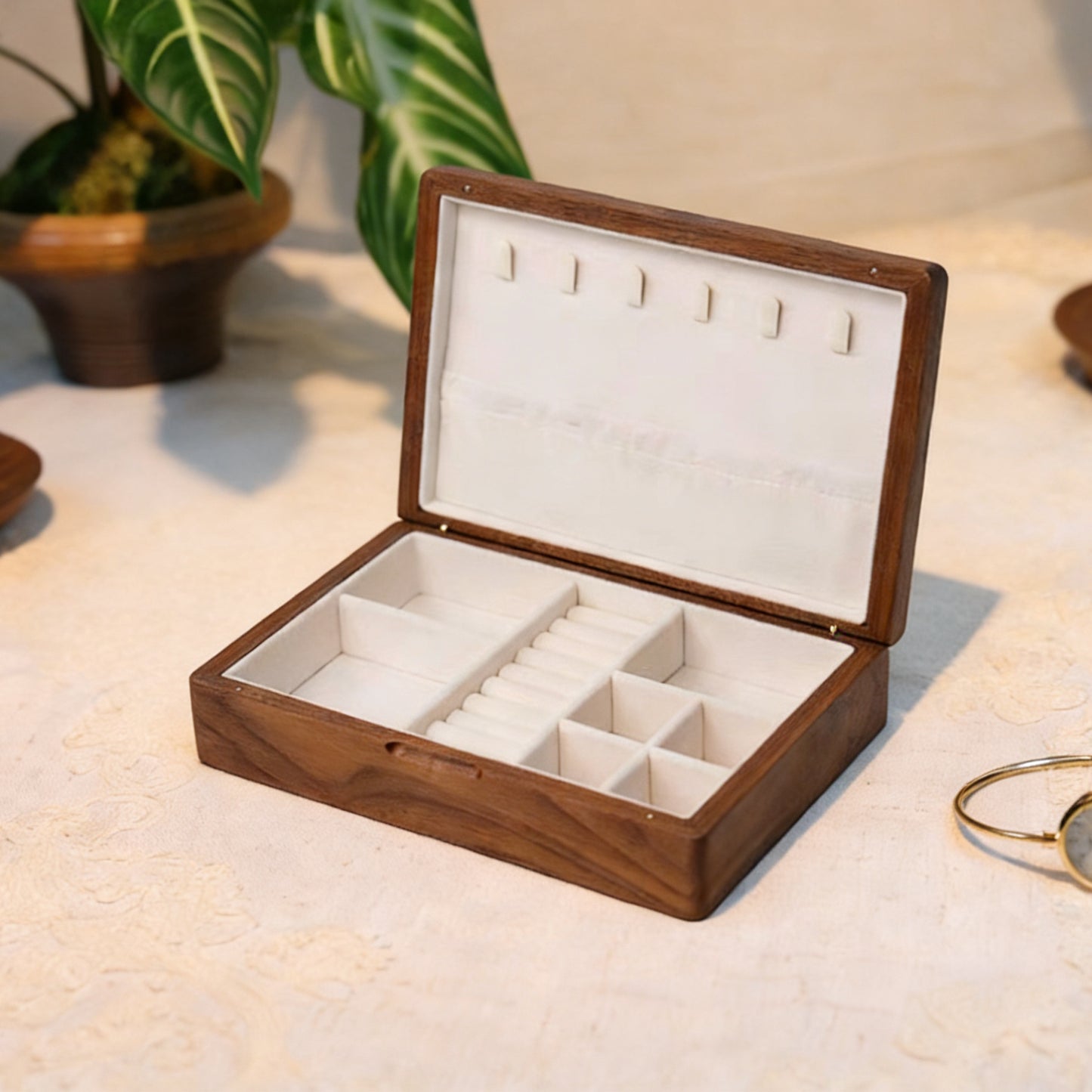 Wooden jewelry box with white interior on a light surface