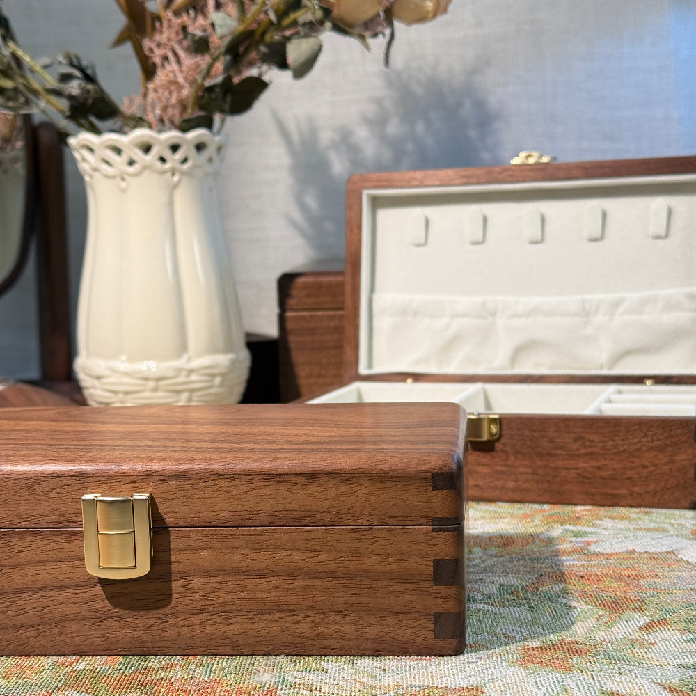 Wooden jewelry box with a gold clasp on a floral-patterned surface